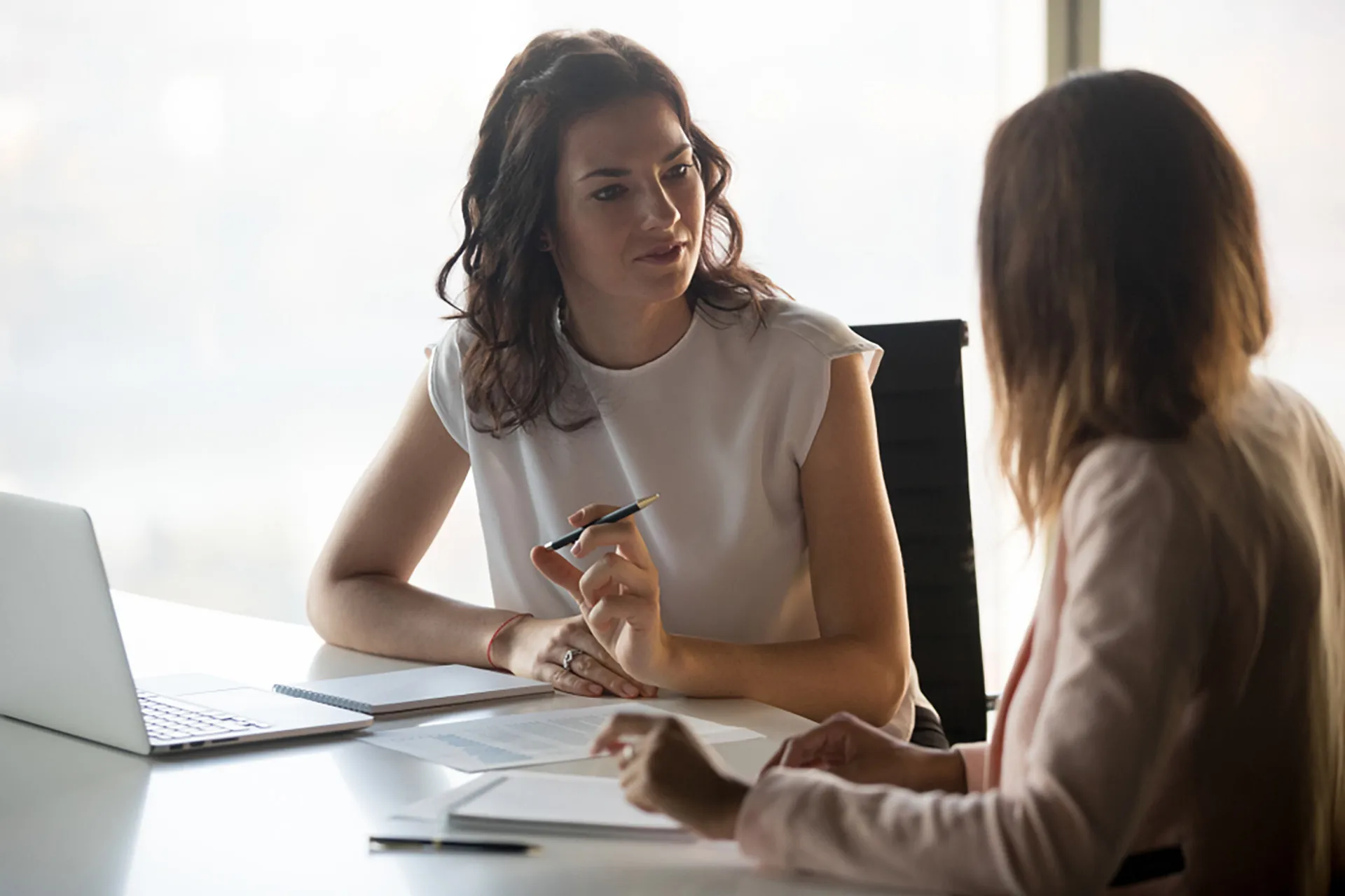 Two women engaged in a conversation while seated at a table.