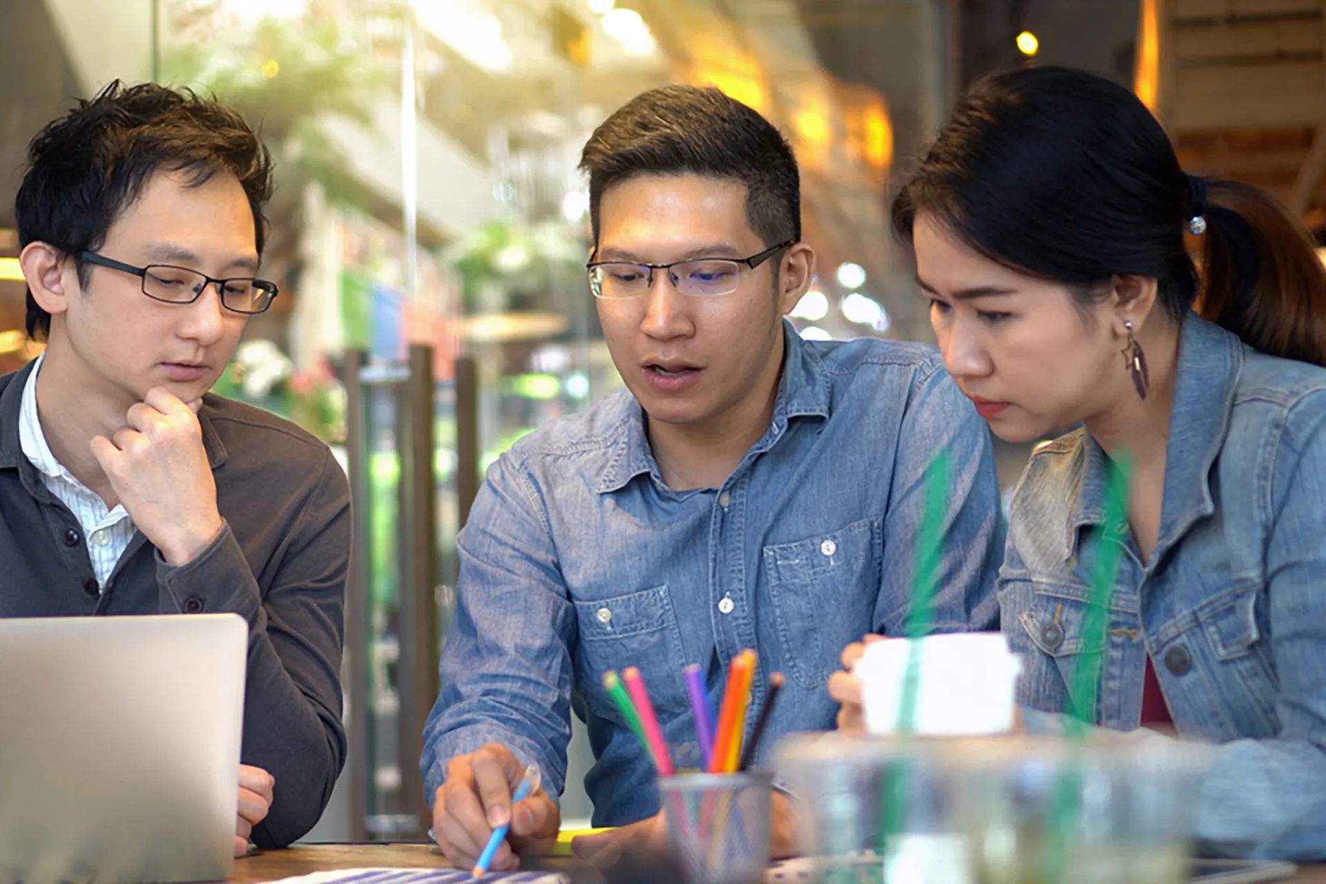 Three software professionals sitting at a table, discussing their work.