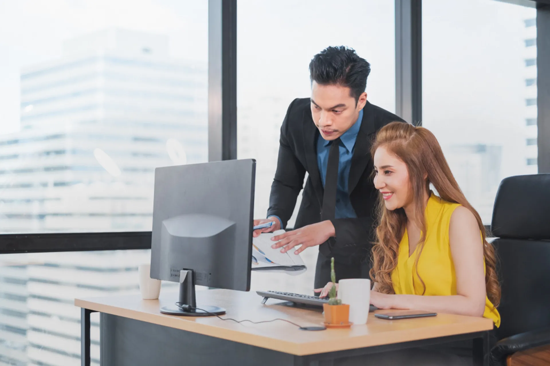 A man and woman discussing work in a professional office environment