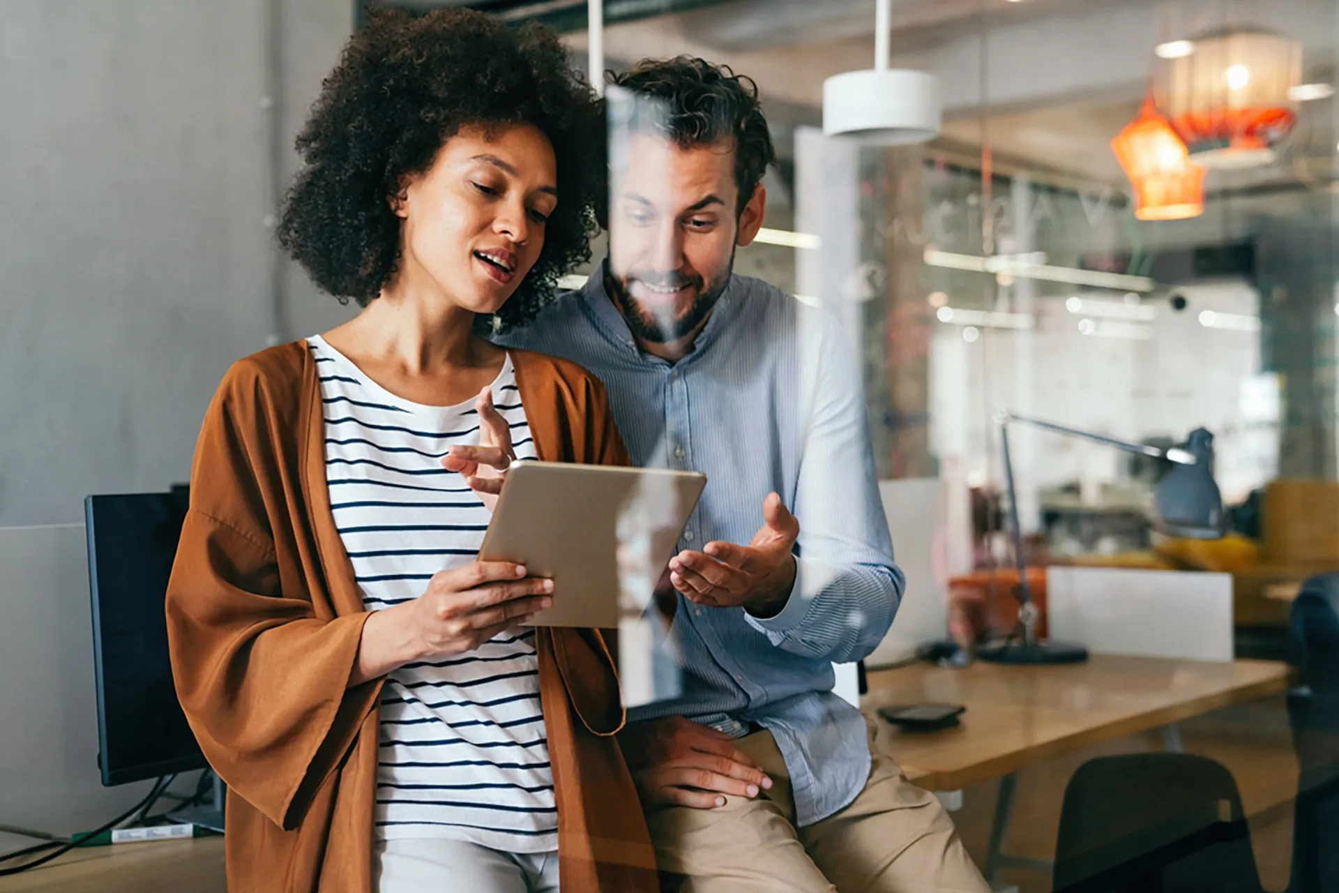 A man and woman reviewing a tablet in a professional office setting.