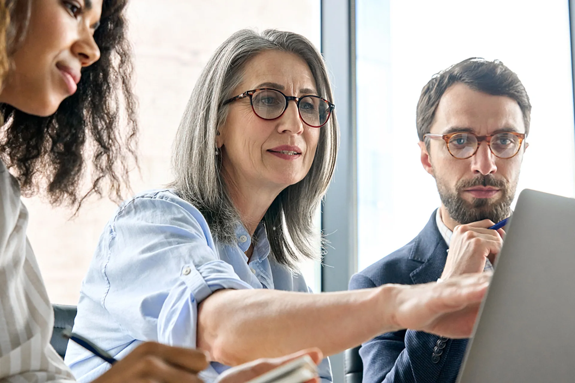  Three finance professionals analyzing data on a laptop, engaged in a business discussion.